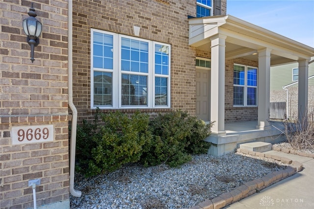 doorway to property with covered porch and brick siding