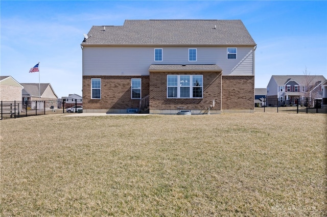 rear view of house featuring a lawn, brick siding, and a fenced backyard