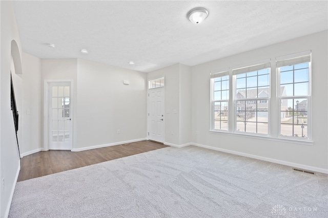 interior space featuring carpet flooring, baseboards, visible vents, and a textured ceiling