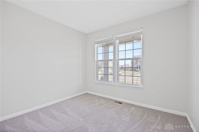 carpeted spare room featuring visible vents and baseboards