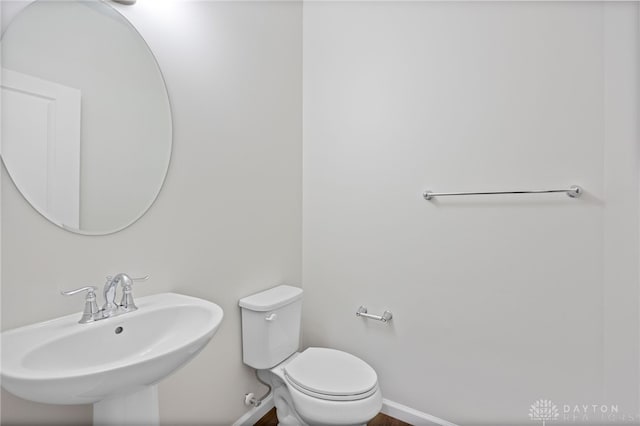 bathroom featuring toilet, baseboards, and a sink