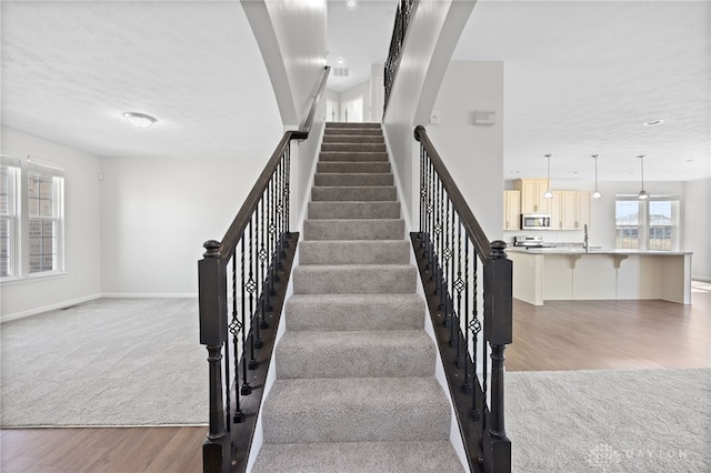 staircase featuring visible vents, carpet flooring, wood finished floors, and baseboards