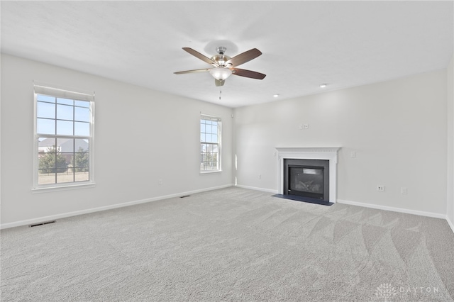 unfurnished living room with visible vents, baseboards, a fireplace with flush hearth, carpet flooring, and a ceiling fan