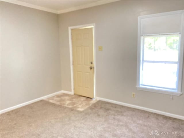 unfurnished room with baseboards, light carpet, a healthy amount of sunlight, and ornamental molding