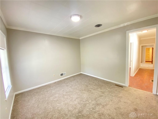 carpeted spare room with visible vents, crown molding, and baseboards