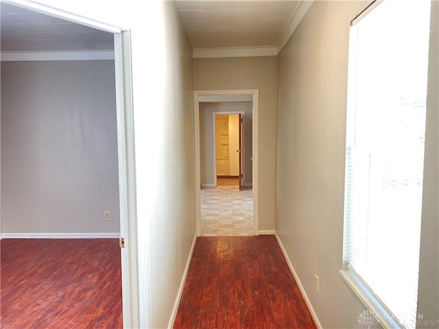 hallway featuring ornamental molding, baseboards, and wood finished floors