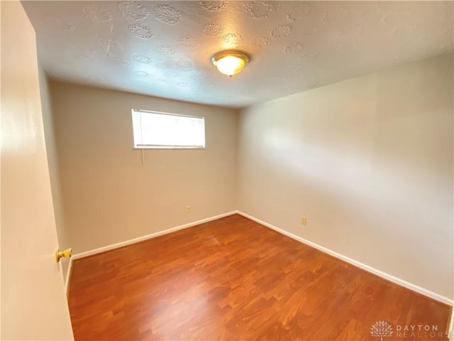 spare room with baseboards and wood finished floors