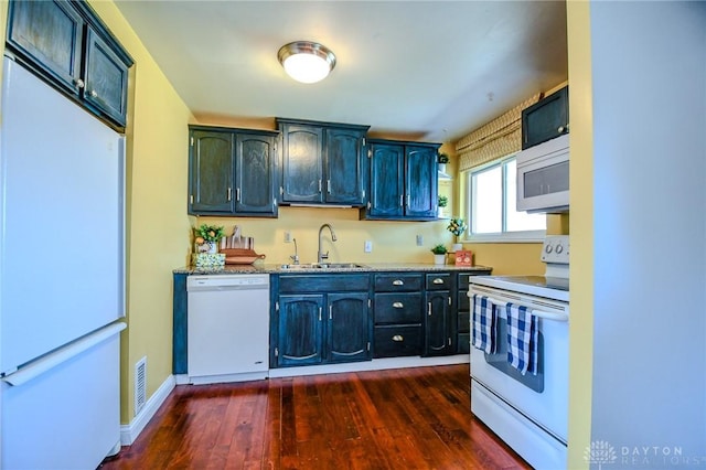 kitchen with white appliances, visible vents, baseboards, dark wood finished floors, and a sink