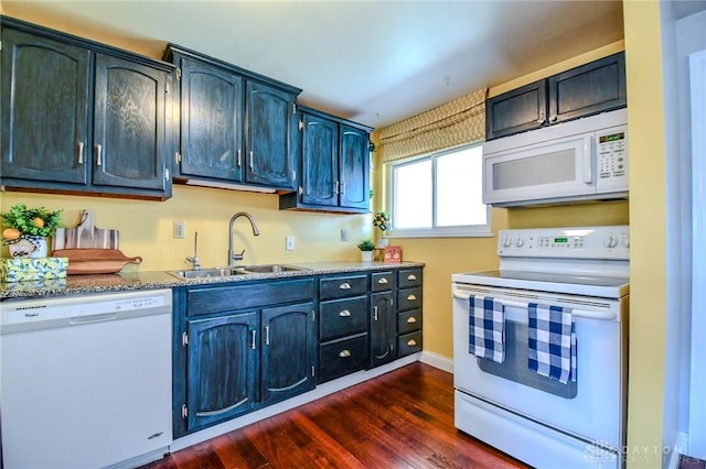 kitchen featuring a sink, blue cabinetry, light stone countertops, white appliances, and dark wood-style flooring