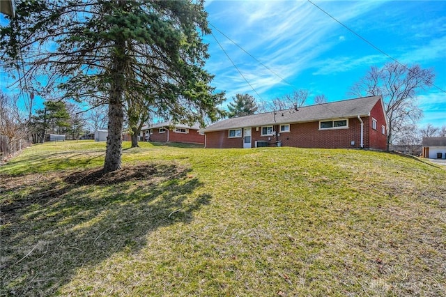 rear view of property featuring brick siding and a lawn