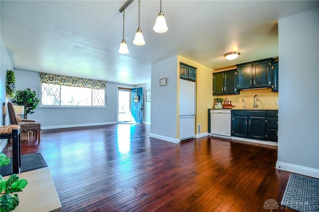 kitchen with white appliances, baseboards, dark wood-type flooring, and a sink