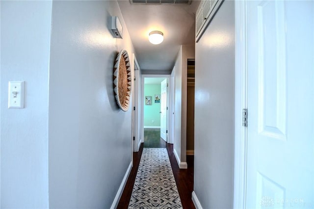 corridor featuring visible vents, baseboards, and dark wood-style flooring