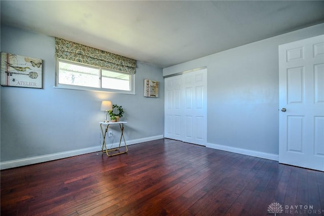 unfurnished bedroom with a closet, baseboards, and hardwood / wood-style flooring