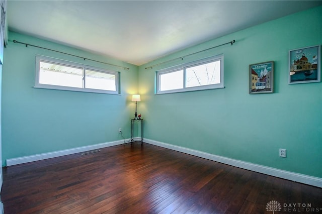 empty room with visible vents, baseboards, and dark wood-style flooring