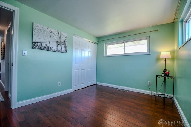 empty room with visible vents, baseboards, and hardwood / wood-style flooring