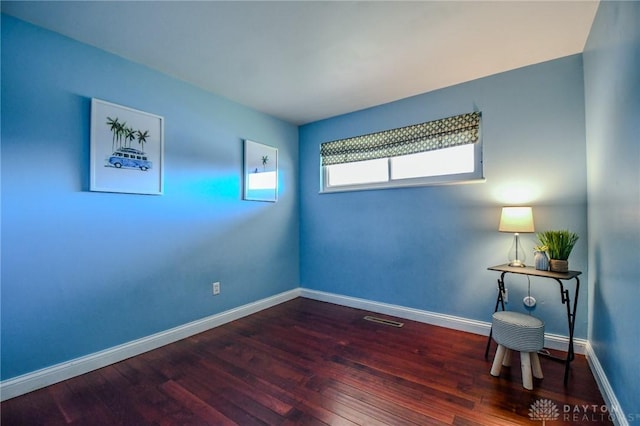 spare room featuring visible vents, baseboards, and wood finished floors