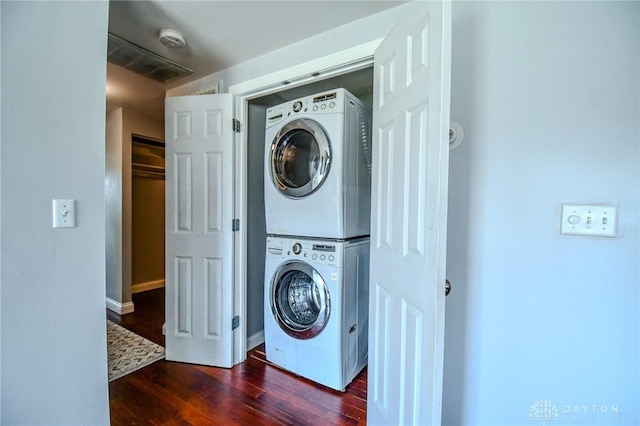 laundry room with dark wood finished floors, laundry area, and stacked washer / dryer