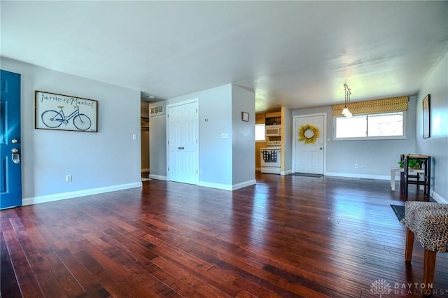 unfurnished living room featuring baseboards and dark wood-type flooring