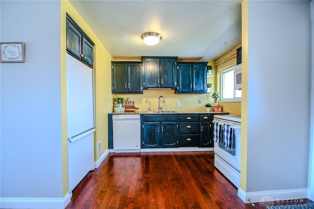 kitchen featuring white appliances, dark wood-style floors, baseboards, a sink, and light countertops