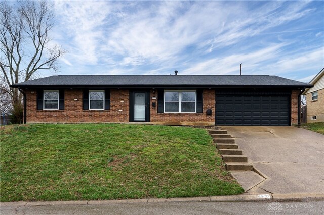 ranch-style home with brick siding, driveway, an attached garage, and a front lawn