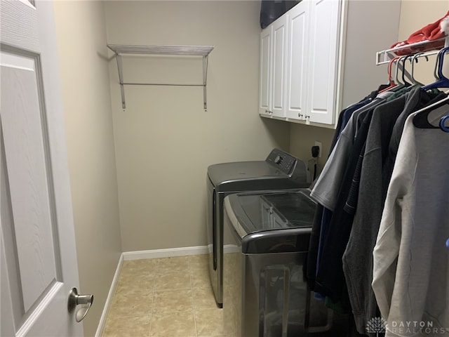 laundry room featuring cabinet space, light tile patterned floors, washer and dryer, and baseboards