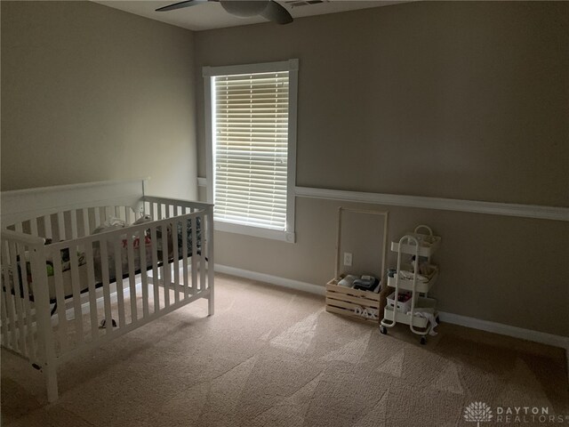 carpeted bedroom with visible vents, baseboards, and a crib