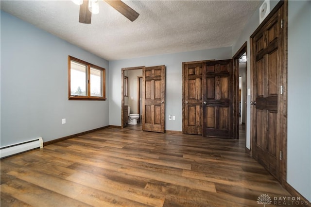unfurnished bedroom featuring a baseboard heating unit, dark wood-style floors, baseboards, and a textured ceiling