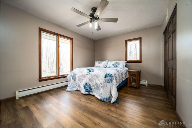bedroom with a baseboard heating unit, wood finished floors, and baseboards