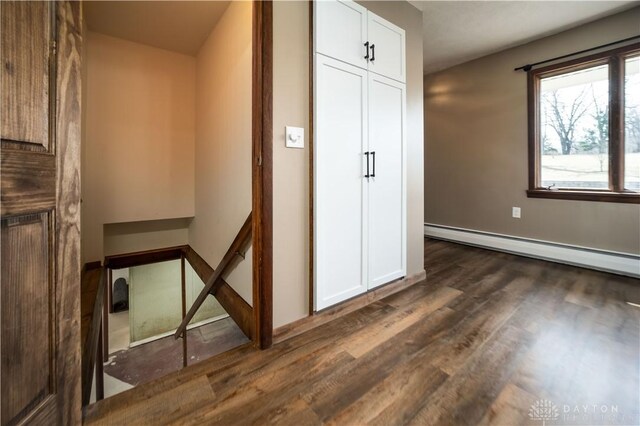 interior space with a baseboard radiator, baseboards, and wood finished floors