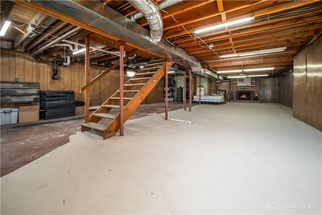 unfinished below grade area featuring a brick fireplace, stairway, and water heater