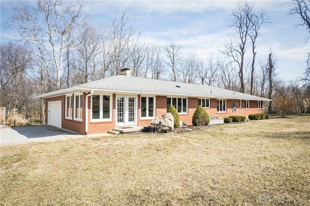 view of front of property featuring french doors, brick siding, an attached garage, and a chimney