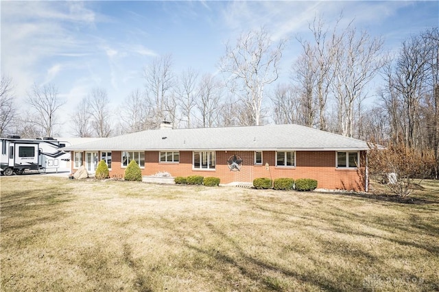 back of property featuring a lawn, a chimney, and brick siding