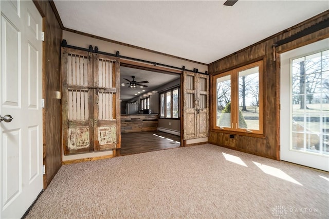 carpeted spare room featuring crown molding, a barn door, and a baseboard radiator