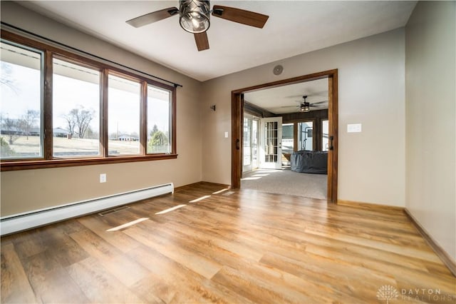 spare room featuring light wood finished floors, baseboards, a ceiling fan, and a baseboard radiator