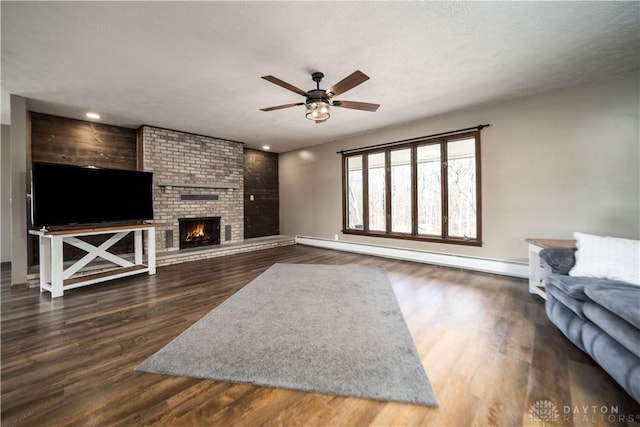 living room featuring ceiling fan, dark wood finished floors, a fireplace, and a baseboard radiator