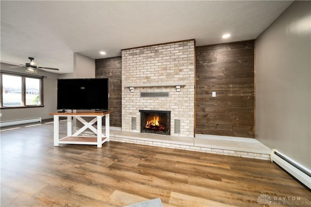 unfurnished living room with a baseboard heating unit, wood finished floors, and ceiling fan