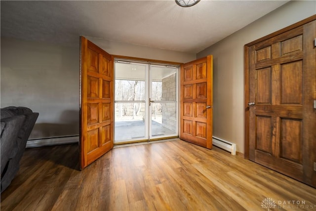 interior space with a baseboard heating unit and wood finished floors