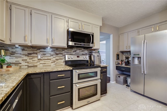 kitchen featuring tasteful backsplash, a textured ceiling, stainless steel appliances, and light stone counters