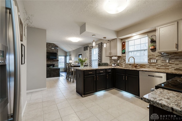 kitchen featuring a sink, backsplash, open floor plan, a peninsula, and dishwasher