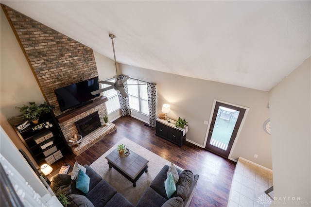 living room with a brick fireplace, wood finished floors, baseboards, and high vaulted ceiling