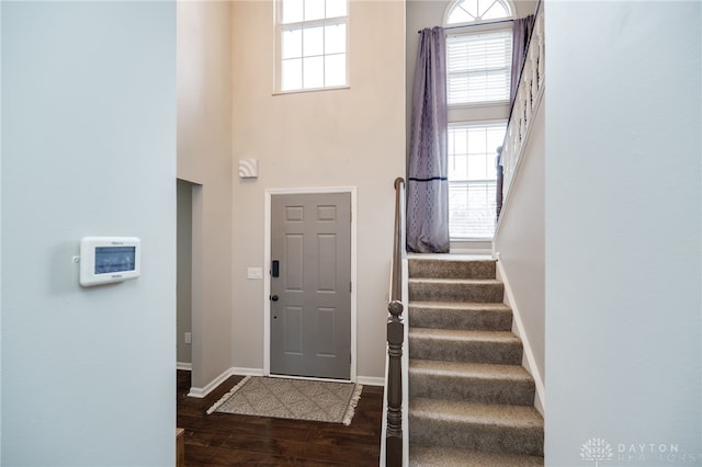 entryway with stairs, a high ceiling, plenty of natural light, and wood finished floors