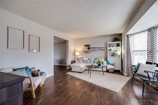 living room featuring a textured ceiling, baseboards, and wood-type flooring