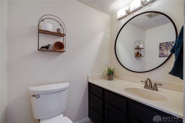 half bathroom featuring visible vents, a textured ceiling, vanity, and toilet