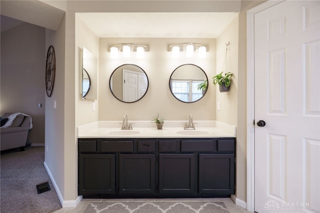 full bathroom featuring a sink, visible vents, baseboards, and double vanity