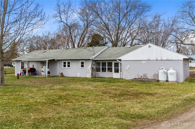 6384 Heffner Rd, Tipp City, OH 45371 - rear view of house with a lawn, a sunroom, and stucco siding