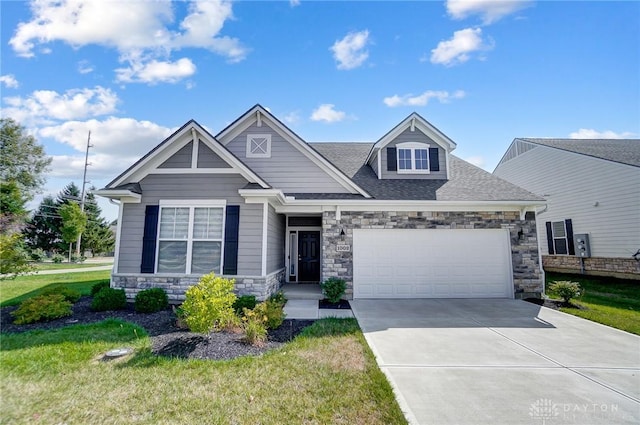 1002 Belfast Dr, Sugarcreek Township, OH 45440 - craftsman-style home featuring stone siding, a shingled roof, concrete driveway, a front yard, and an attached garage