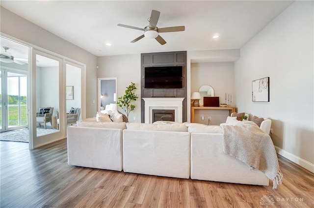 1002 Belfast Dr, Sugarcreek Township, OH 45440 - living area featuring a fireplace, light wood-style flooring, a ceiling fan, and baseboards