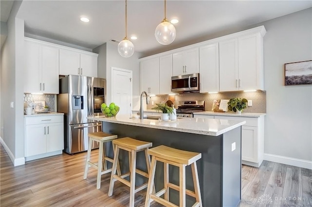 1002 Belfast Dr, Sugarcreek Township, OH 45440 - kitchen featuring a kitchen island with sink, appliances with stainless steel finishes, a breakfast bar, and light wood finished floors