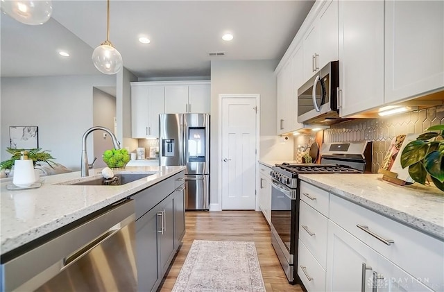 1002 Belfast Dr, Sugarcreek Township, OH 45440 - kitchen with light wood-style flooring, a sink, tasteful backsplash, appliances with stainless steel finishes, and white cabinets