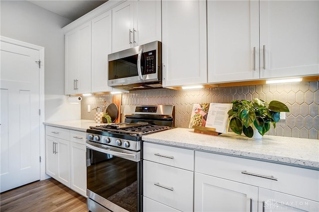 1002 Belfast Dr, Sugarcreek Township, OH 45440 - kitchen with light stone countertops, light wood finished floors, stainless steel appliances, decorative backsplash, and white cabinets